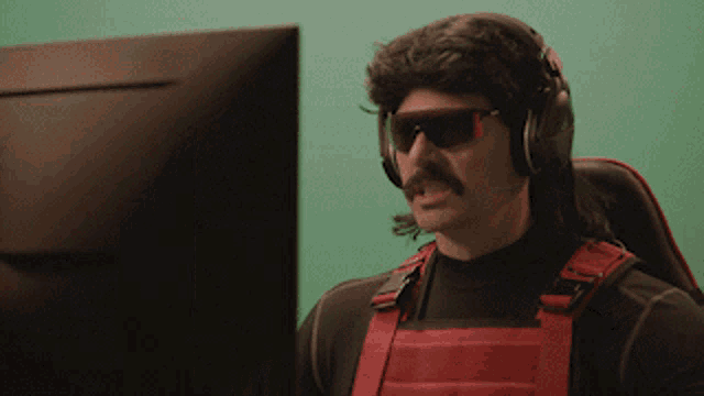 a man wearing sunglasses and headphones is looking at a computer monitor