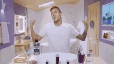a man in a white shirt is flexing his muscles in a bathroom