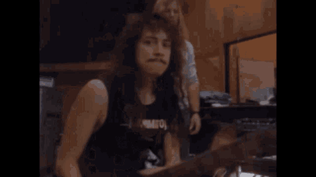 a man with long hair and a mustache wears a shirt with the word kiss on it