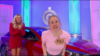 a woman in a pink shirt with the word minimum on it stands in front of a red car
