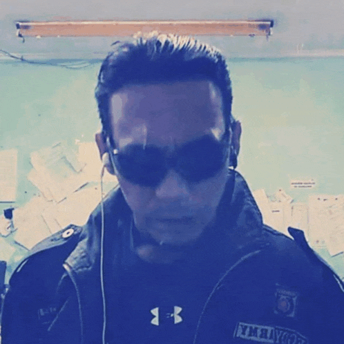 a man wearing sunglasses and a jacket with the letter b on it