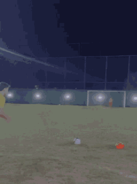 a man is kicking a soccer ball on a field at night