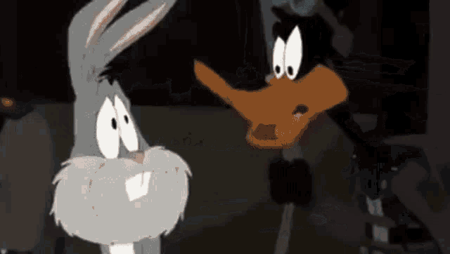 bugs bunny and daffy duck are standing next to each other in a dark room in a cartoon .