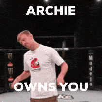 a man in a white shirt is dancing in a ring with the words archie owns you on the bottom