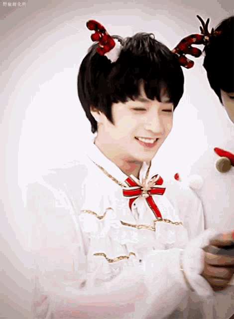 a boy wearing reindeer antlers and a bow tie smiles