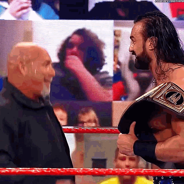 a man with a beard and a championship belt talks to another man