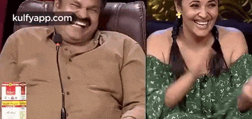 a man and a woman are laughing together while sitting next to each other in front of a microphone .