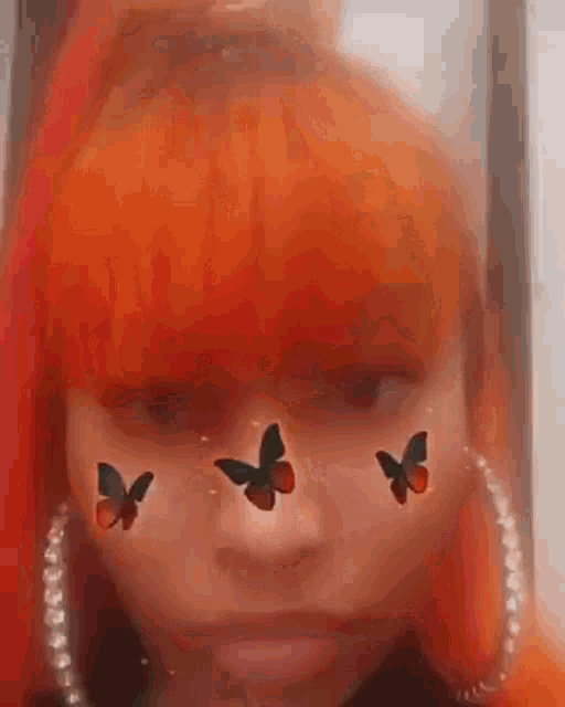 a girl with red hair and butterflies on her face is making a funny face .