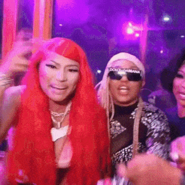 a woman with red hair is standing next to a man wearing sunglasses and a dolce & gabbana headband .