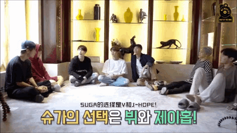 a group of young men are sitting on the floor in front of a shelf with chinese writing on it