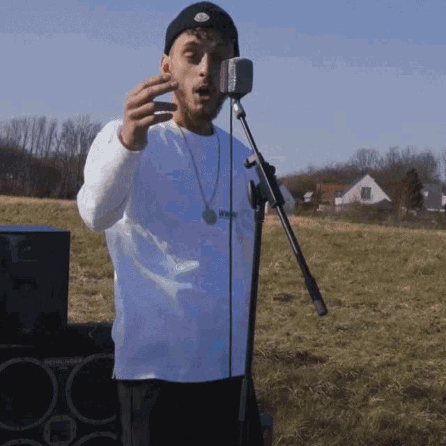 a man is singing into a microphone with a necklace that says i am