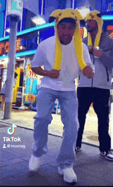 a man wearing a pikachu hat is dancing on a street