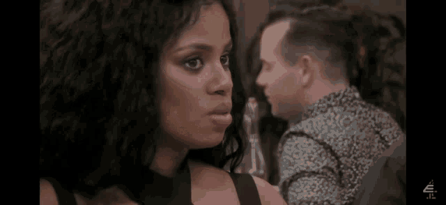 a woman is looking at a man while sitting at a table with a bottle of wine .