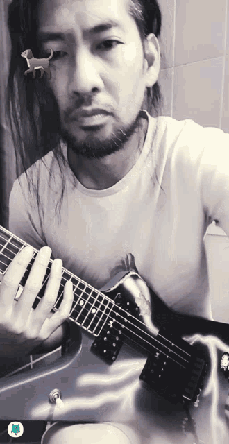 a man with long hair playing a guitar with a cat on his face
