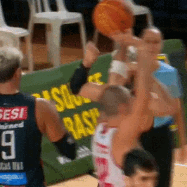 a basketball player wearing a sesi jersey jumps to catch a basketball