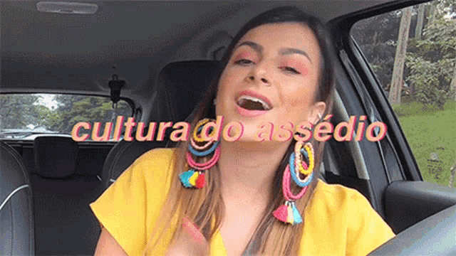 a woman in a yellow shirt is singing in a car with the words cultura do asserio behind her