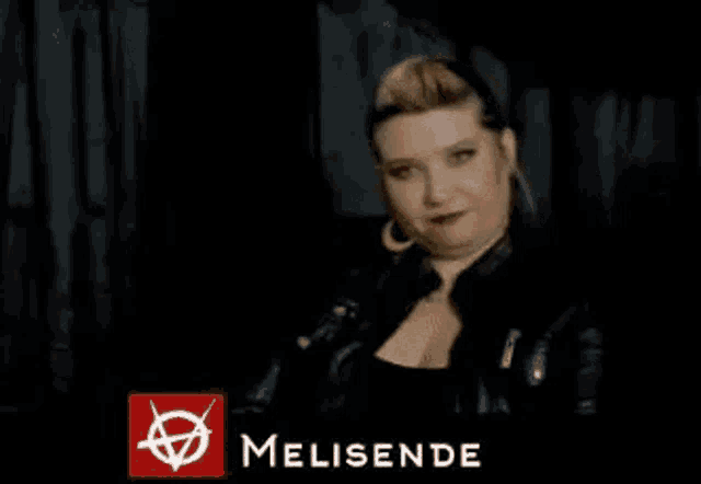 a woman in a black leather jacket is sitting in a dark room .