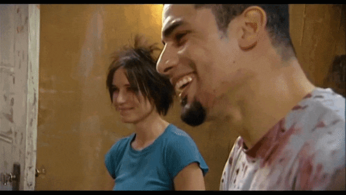 a man and a woman are laughing together in a room