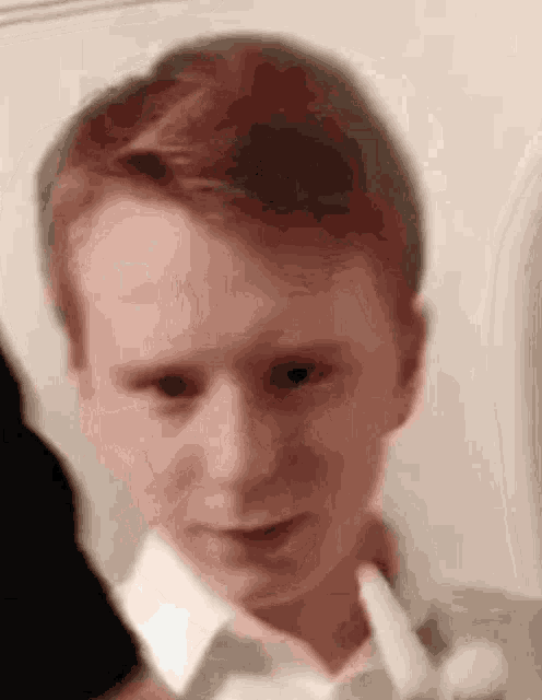 a close up of a person 's face with a white shirt on