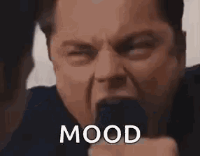 a man in a suit and tie is making a funny face with his mouth open and the word mood on his face .