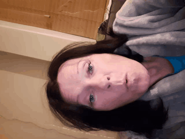 a woman laying down with a blanket around her head