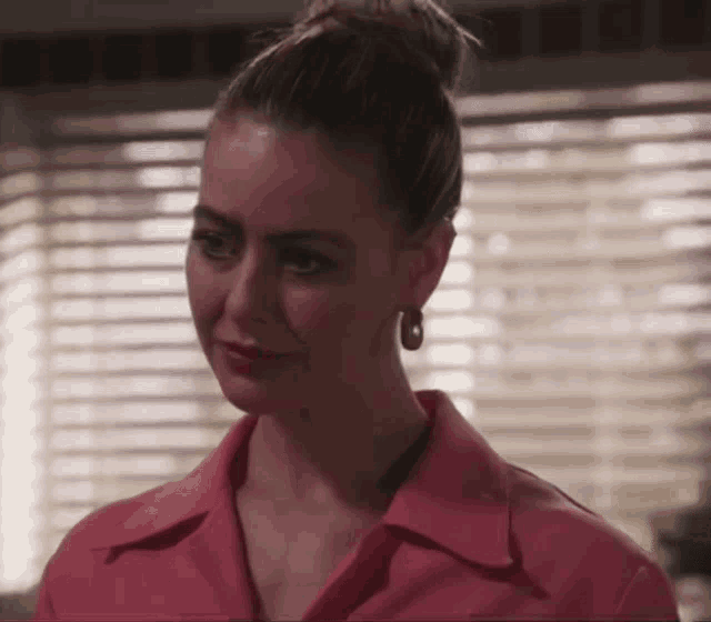 a woman wearing a pink shirt and earrings looks at something