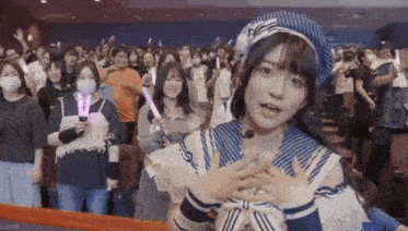 a girl in a sailor outfit is standing in front of a crowd of people holding glow in the dark sticks .