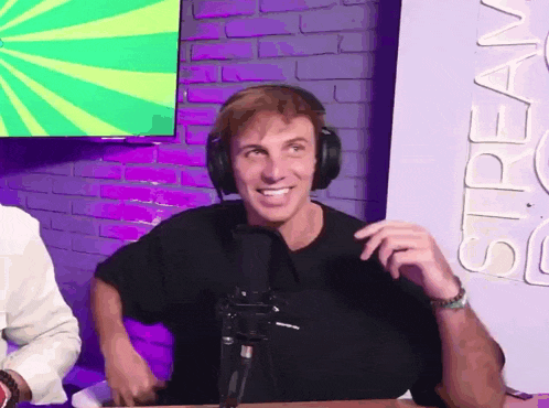 a man wearing headphones is sitting in front of a microphone and smiling