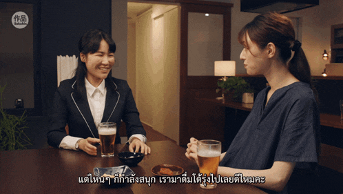 a woman sitting at a table with a glass of beer and another woman with chinese writing