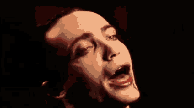 a close up of a man 's face in a red light with his mouth open .