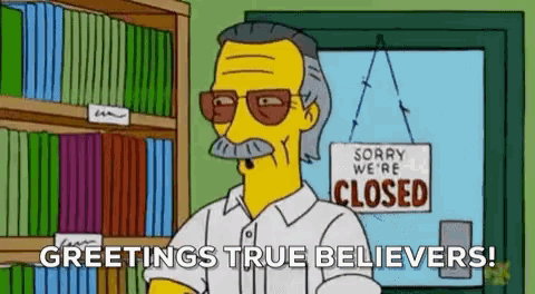 stan lee is standing in front of a closed sign in a library .