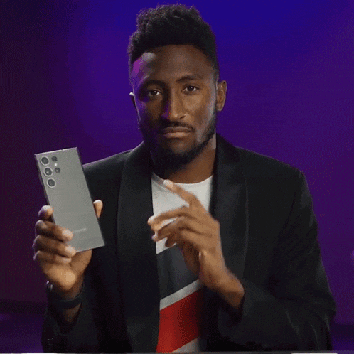 a man in a suit is holding a cell phone with the words really good below him