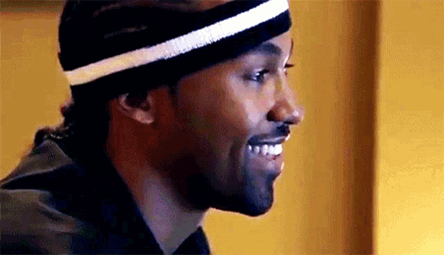 a man wearing a black headband with a white stripe on it smiles