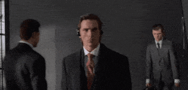 a man in a suit and tie wearing headphones stands in a dark room