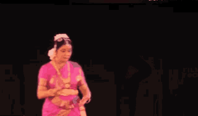 a woman in a pink dress is dancing in the dark