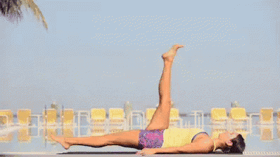 a woman is laying on her back on a yoga mat with her legs up .