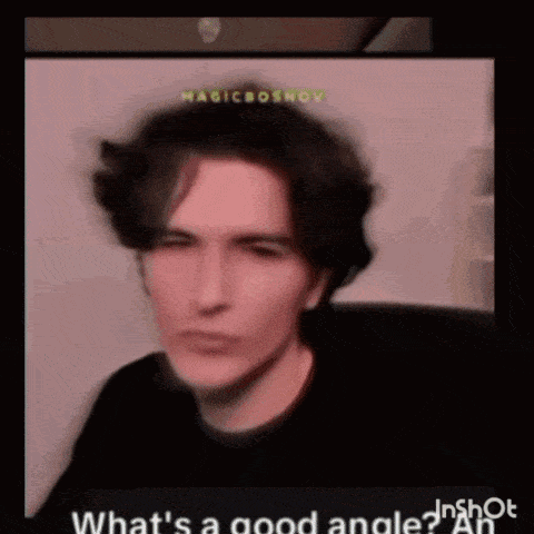 a young man is making a funny face and pointing his finger at the camera .