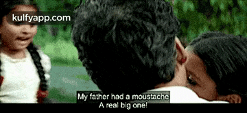 a man with a moustache is being kissed by a girl .