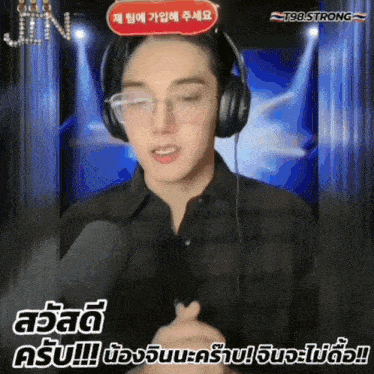 a man wearing glasses and headphones is talking into a microphone with a t98 strong logo in the background