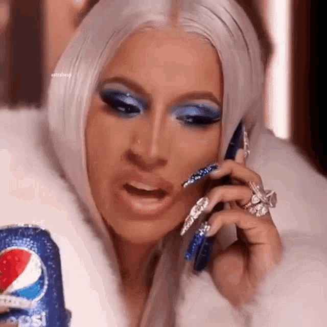 a woman talking on a cell phone while holding a pepsi can