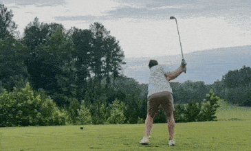 a man is swinging a golf club at a golf ball