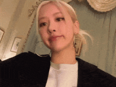 a woman with blonde hair is wearing hoop earrings and a white shirt