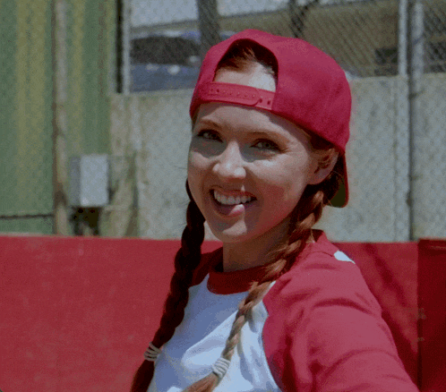 a woman wearing a red hat and a white shirt smiles at the camera