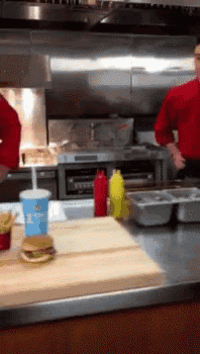 two men in red uniforms are preparing food in a restaurant