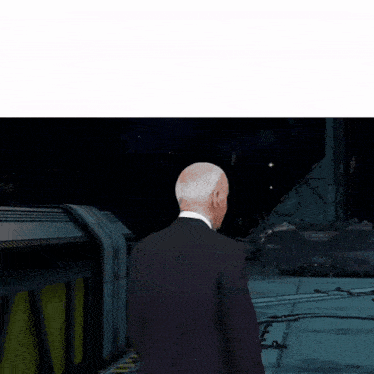 a man in a suit is standing in front of a space ship and talking to a master chief