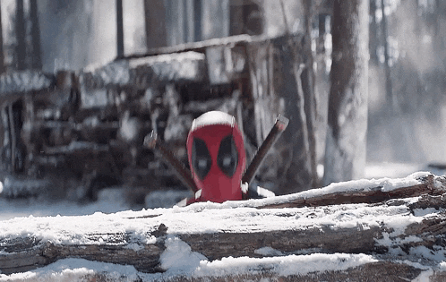deadpool is peeking out from behind a log in the snow .