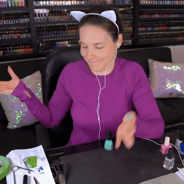 a woman wearing a cat ear headband is sitting at a desk with nail polish