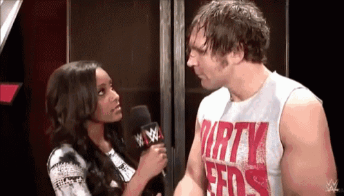 a woman is talking to a wrestler wearing a shirt that says dirty birds .