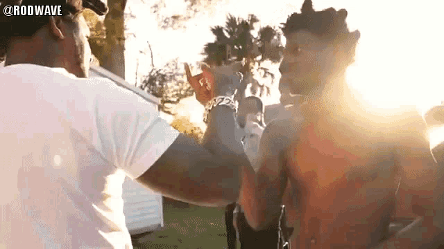 a man in a white shirt is giving another man a high five .