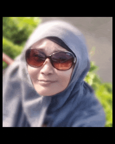 a woman wearing a hijab and sunglasses is smiling for the camera